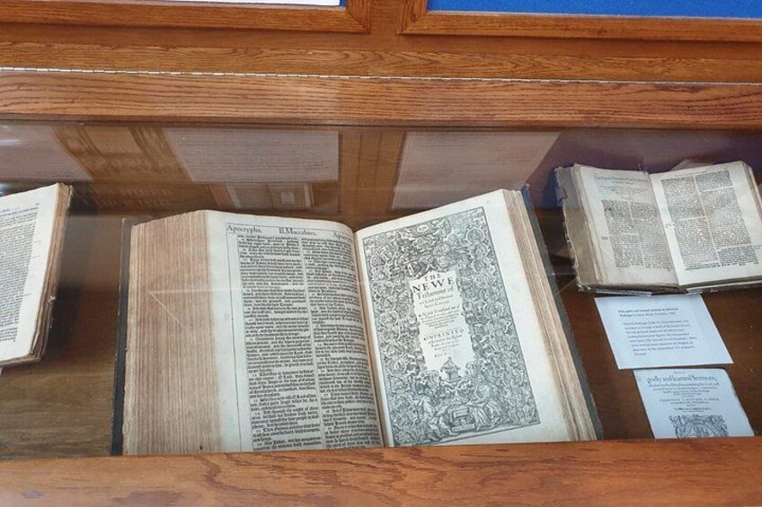 An open book with ornate designs and text, placed on a wooden surface. 2