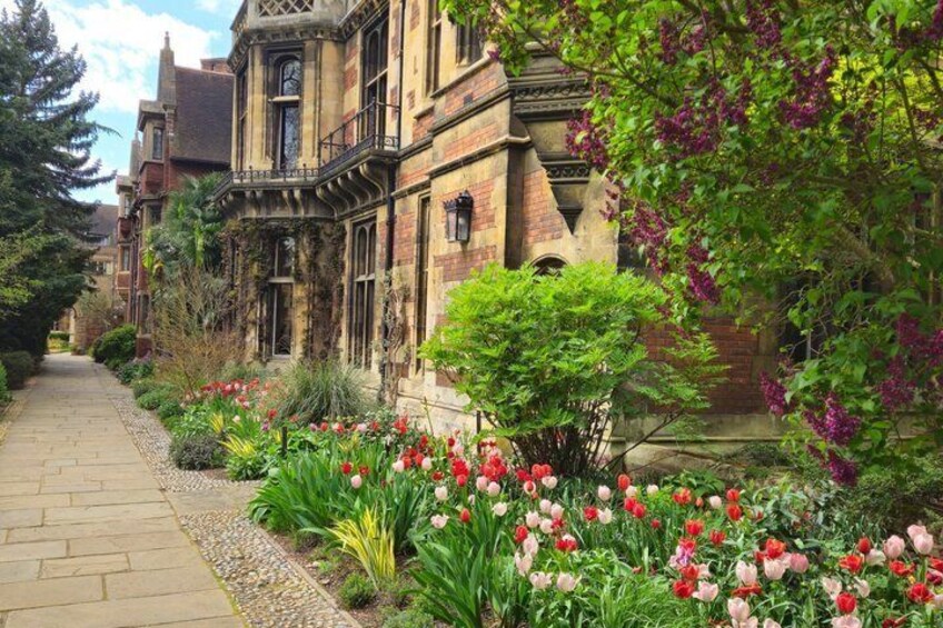 A historic building with a garden of red and pink tulips. 2