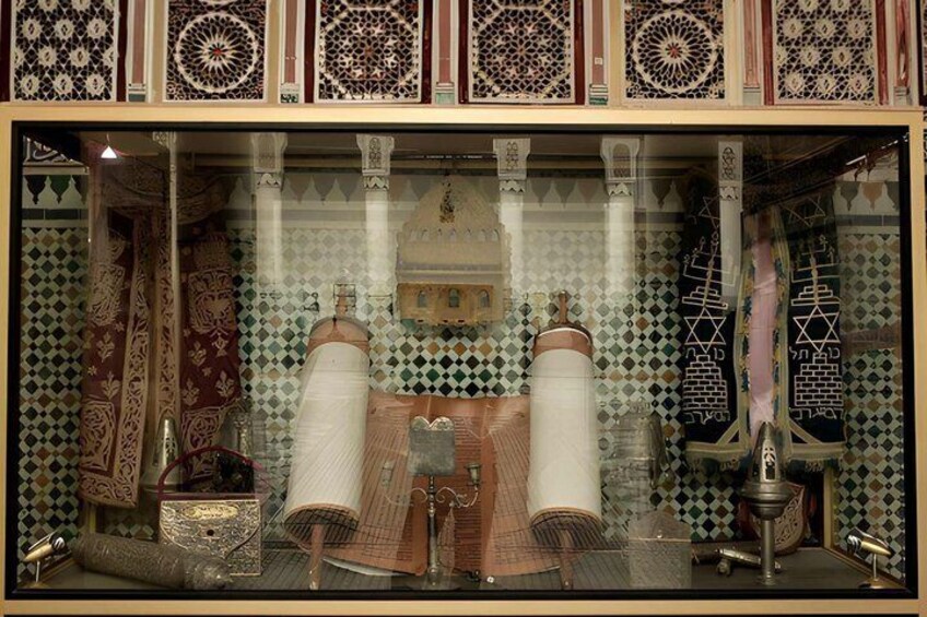 A display of traditional textiles and pottery, including a patterned wall and a hanging tapestry. 4
