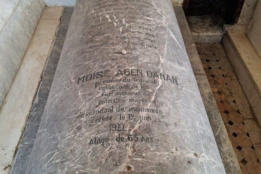 A marble tombstone with inscriptions, located in a tiled room. 3