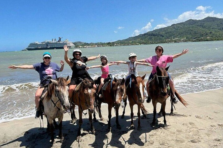 A group of people on horseback on a beach with a cruise ship in the background. 3