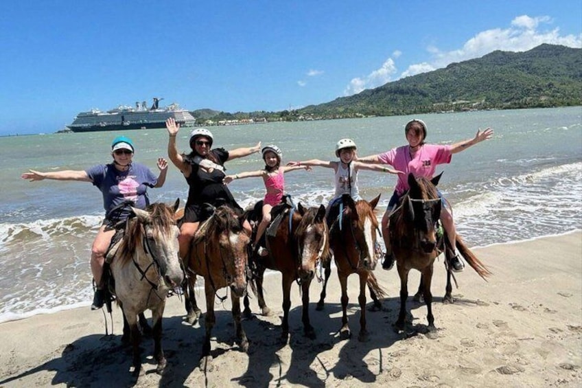 A group of people on horseback on a beach with a cruise ship in the background. 3