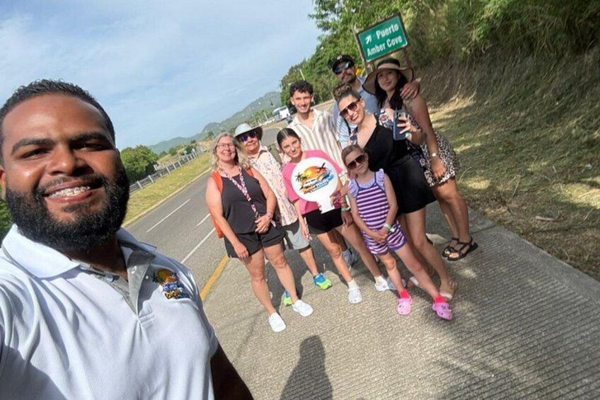 A group of people on a road with a sign that reads 'Puerto Amber Cove'. 2