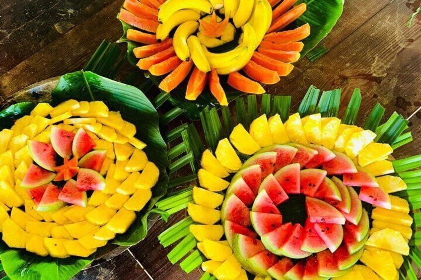 A fruit arrangement with bananas, mangoes, and watermelon slices on banana leaves. 5