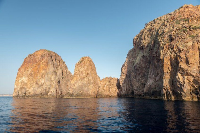 A coastal landscape with large rock formations and calm water. 2