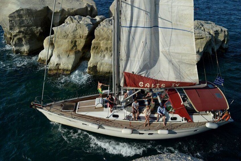 A sailboat named 'GOLTS IV' with passengers and crew, sailing near rocky coastlines. 1
