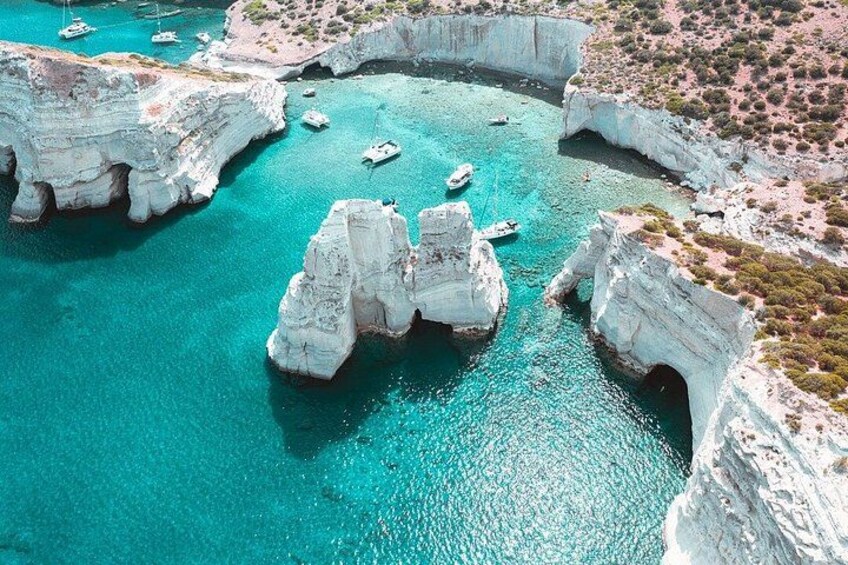 A coastal area with white cliffs, turquoise water, and boats. 3