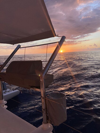 A boat's railing, a cushion, and the ocean with a sunset in the background. 2