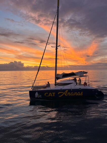 A sailboat named 'CAT Ananas' on calm waters during sunset. 1