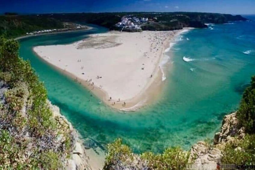 A coastal landscape with a sandy beach, clear turquoise waters, and a rocky shoreline. 2