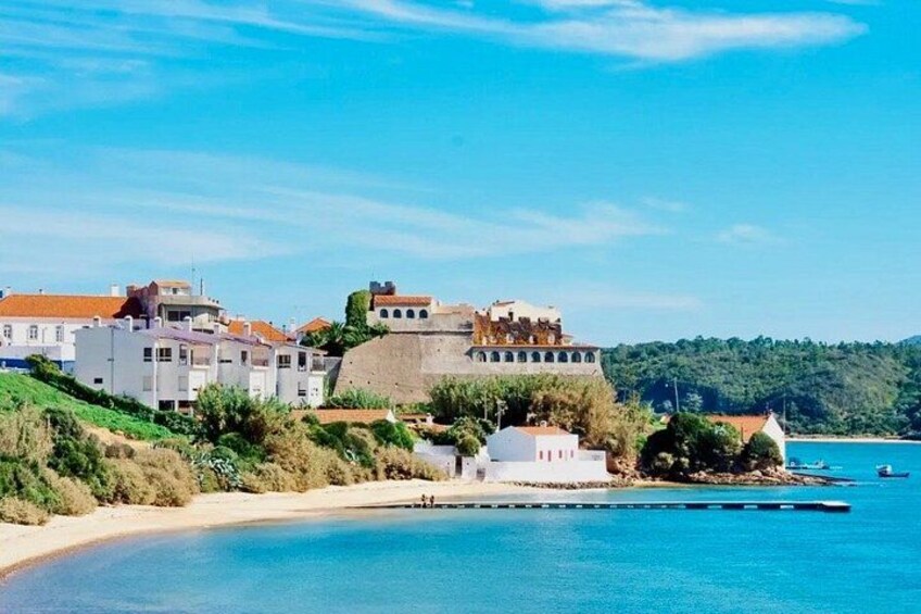 A coastal town with buildings, a beach, and a clear blue sea. 3