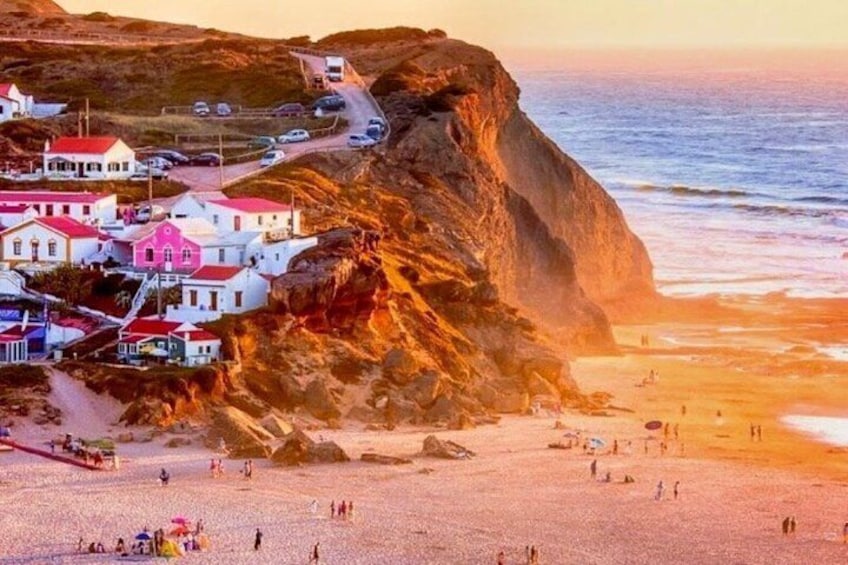 A coastal town with buildings on a cliff, a beach, and the ocean. 1