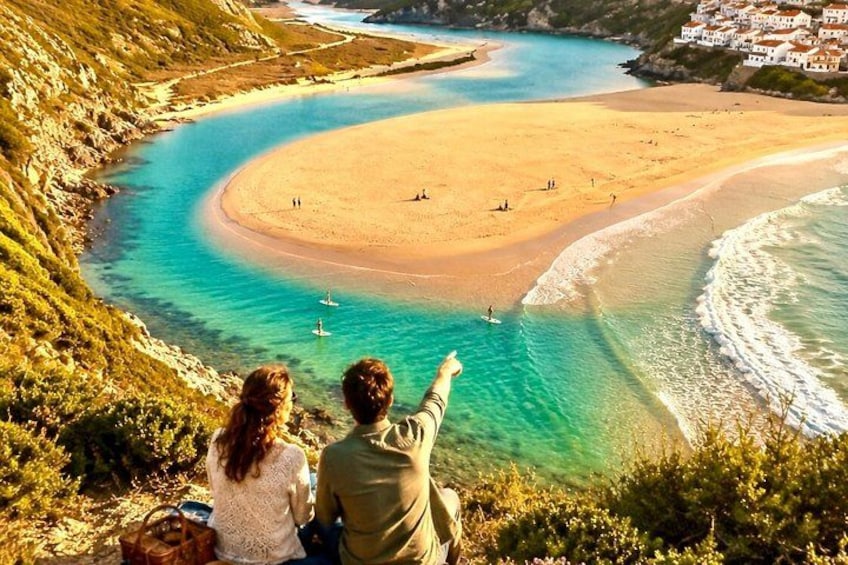A coastal landscape with a sandy beach, clear turquoise waters, and a hilly backdrop. 1
