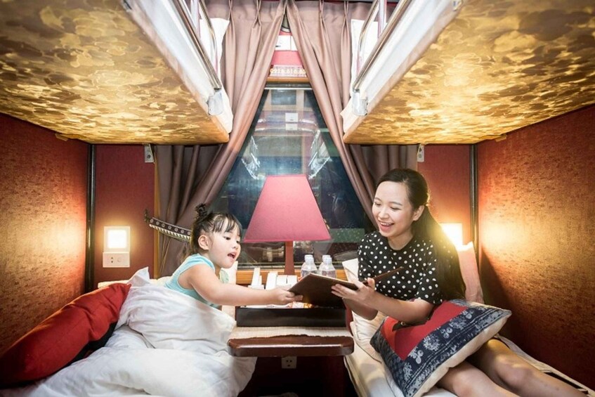 A room with a bed, a table, a lamp, and curtains. 2