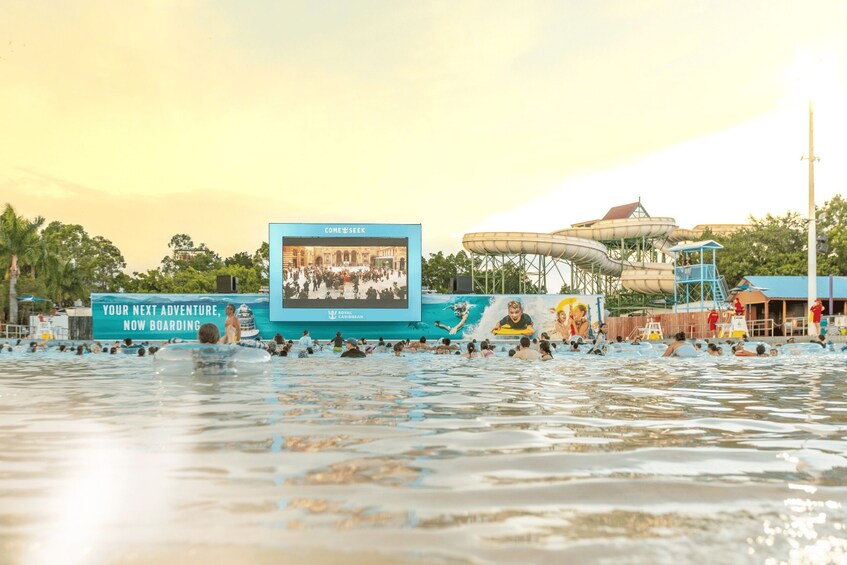 A water park with a large screen advertising 'COME SEEK' and 'YOUR NEXT ADVENTURE, NOW BOARDING.' 5