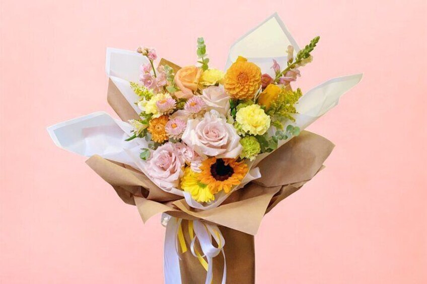 A bouquet of flowers with various colors and types, wrapped in brown paper and tied with a yellow ribbon. 2
