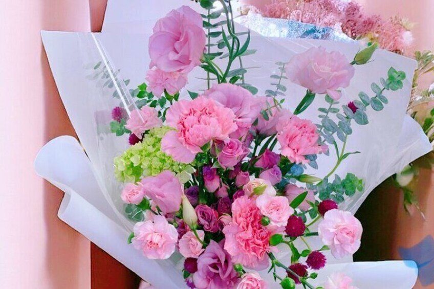 A bouquet of pink and purple flowers wrapped in white paper. 4