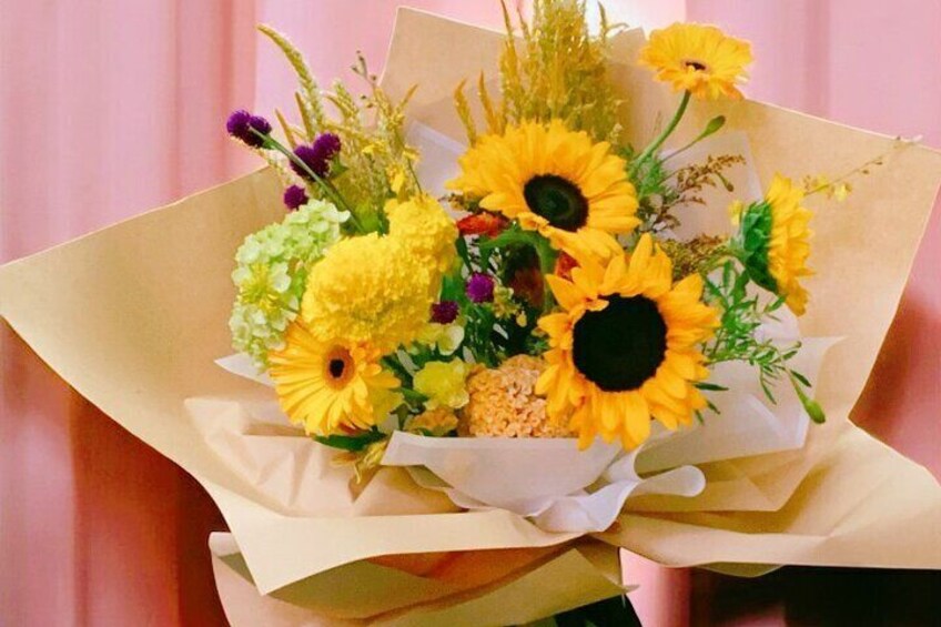A bouquet of sunflowers and other flowers wrapped in brown paper. 5