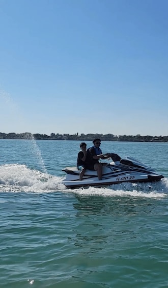 Two people jet-skiing on a calm lake with a clear sky. 2