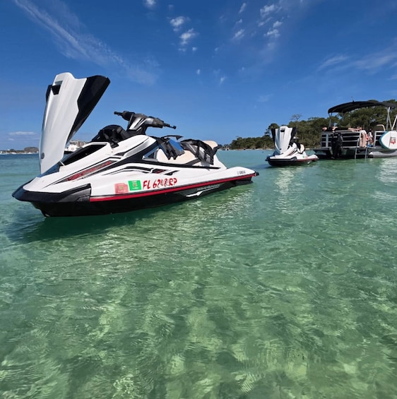 A white speedboat with 'FL 62URP' on its side, docked at a marina with clear turquoise water. 3