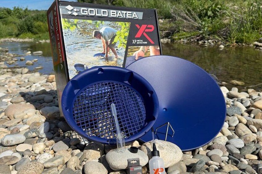 A blue fishing device, a box labeled 'GOLD BATEA XR', and a rocky riverbank. 5