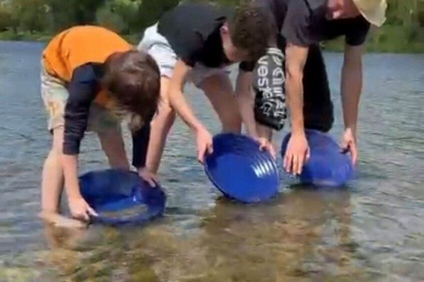People in a river, holding blue containers. 1