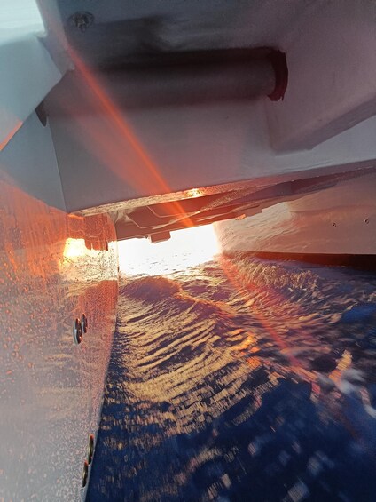 A boat's interior with a view of the ocean through the open bow, waves visible outside, and a sunset. 3