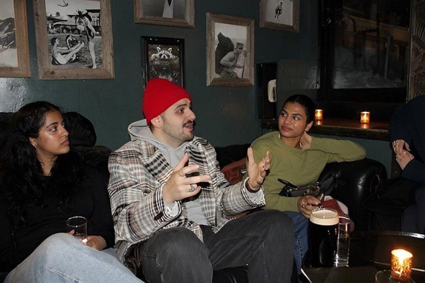 A group of people sitting on a couch in a room with framed pictures on the wall. 3