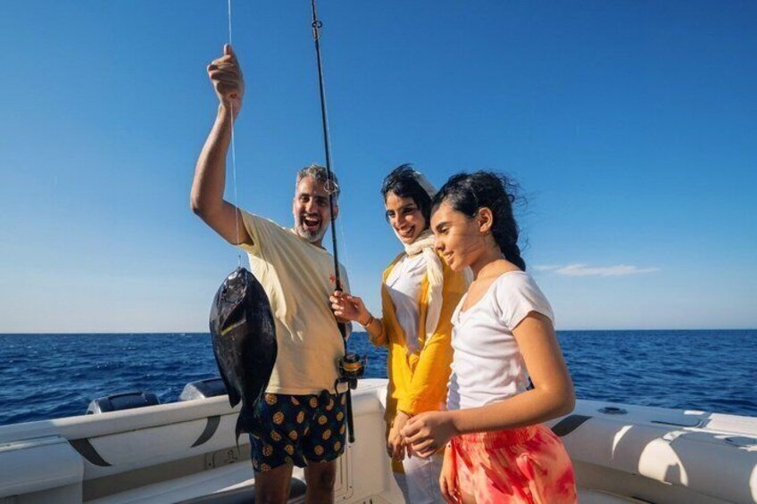 Three people on a boat with a fishing rod, ocean in the background. 5