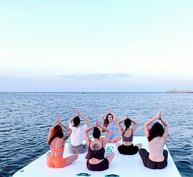 A group of people performing yoga on a boat in the ocean. 1