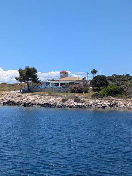 A coastal building with a tower, surrounded by rocks and vegetation. 2