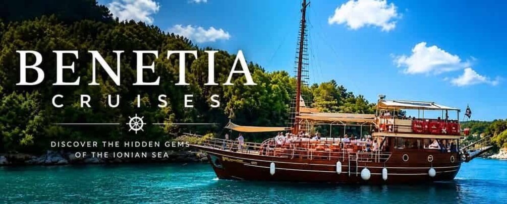 A boat named Benetia Cruises on the Ionian Sea with a clear sky and forested coastline. 5