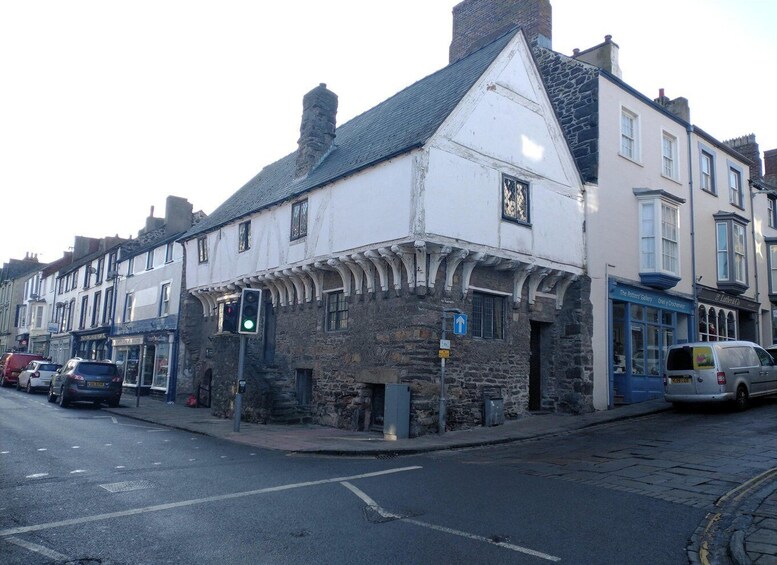 A historic building with stone walls and a white facade, a traffic light, and parked cars on a street. 2