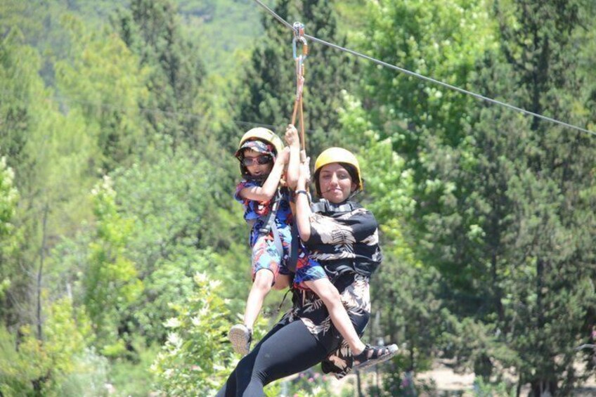Two people zip-lining through a forested area. 4