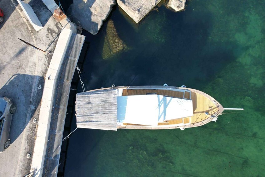 A small wooden boat docked at a pier with clear water. 2