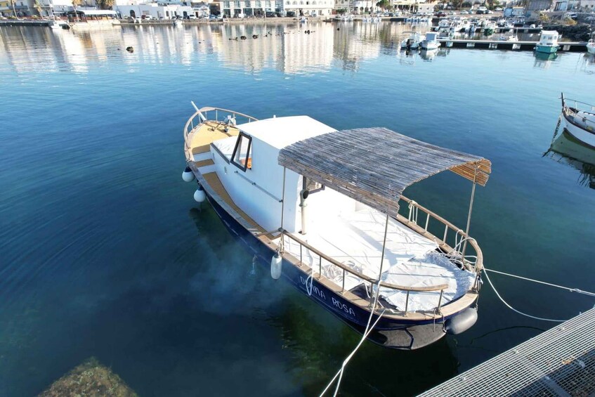 A small boat docked at a marina with calm water and other boats in the background. 3