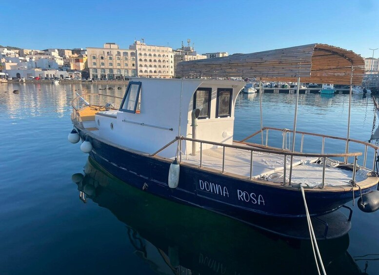 A small boat named 'DONNA ROSA' docked at a marina with buildings in the background. 1