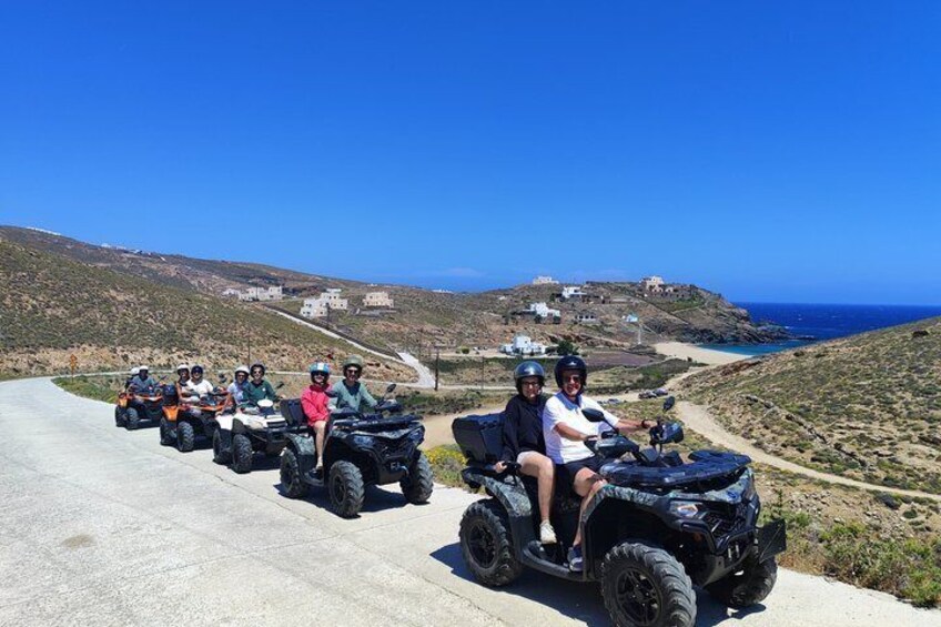 A group of people on ATVs on a coastal road with a view of the sea and hills. 2