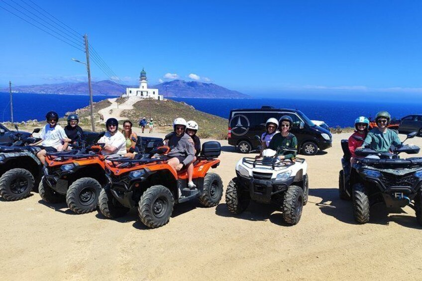 A group of people on ATVs with a lighthouse and ocean in the background. 3