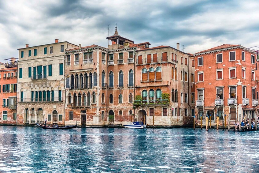 A canal with gondolas and historic buildings with arched windows and balconies. 5