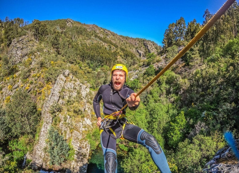 A person bungee jumping with a rope, surrounded by a mountainous landscape and greenery. 1