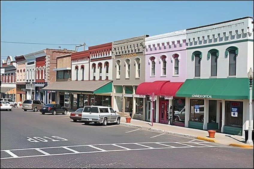 A street lined with historic buildings, a stop sign, and parked cars. 4