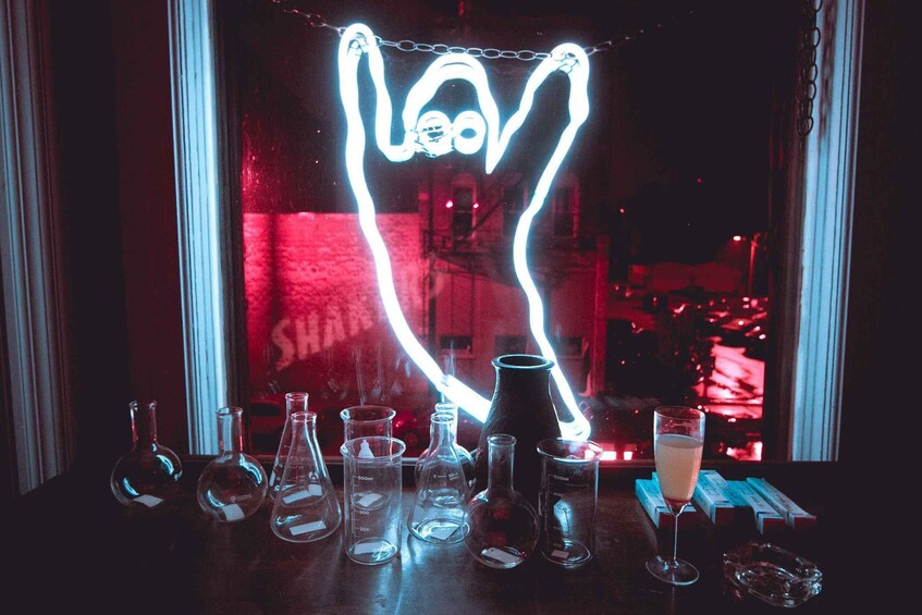 A bar with various glassware and a neon sign. 3