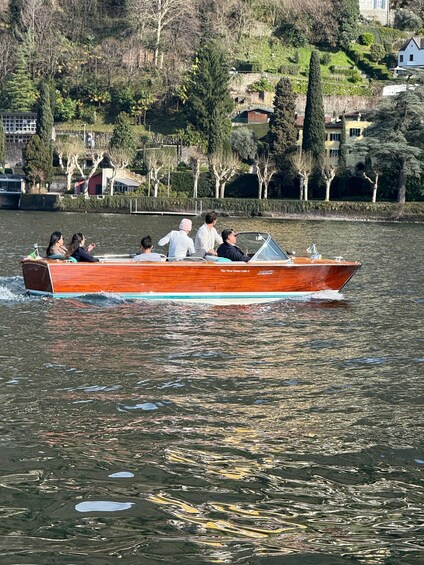 A red boat with passengers on a lake surrounded by trees and houses. 5