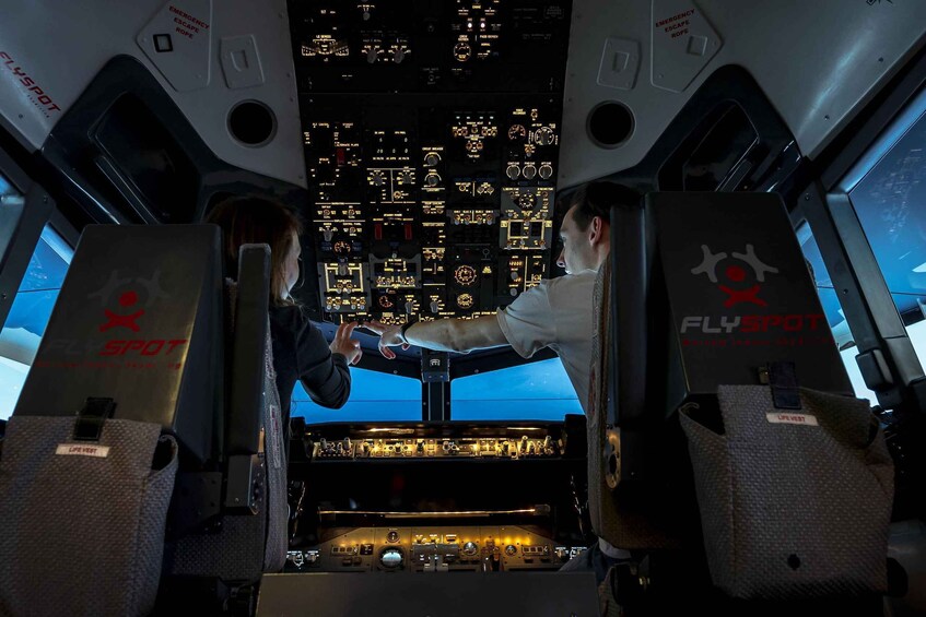 A cockpit with multiple control panels and a view of a cityscape at night. 4