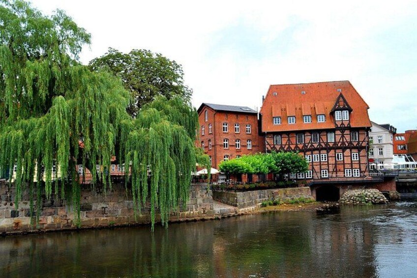 A river with a weeping willow tree, a traditional half-timbered building, and a stone bridge. 2