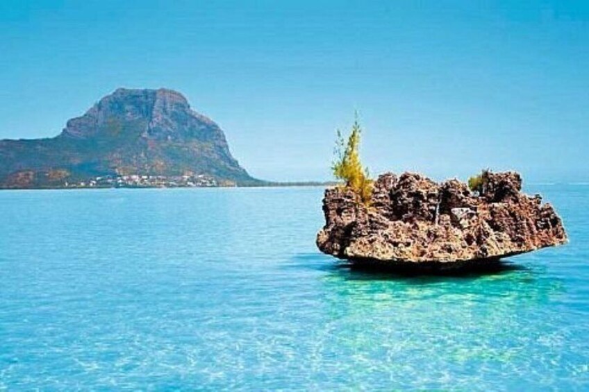A clear blue sea with a rocky island and a mountain in the background. 3