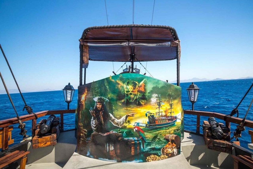 A ship's deck with a pirate-themed mural, a parrot, and a ship in the background. 5