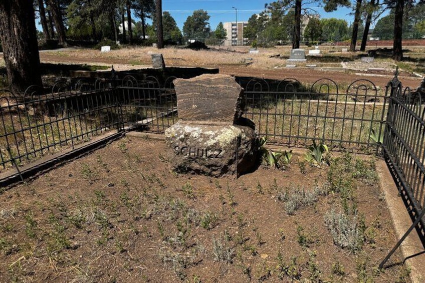 A cemetery with headstones, a fenced area, and a large stone monument. 5