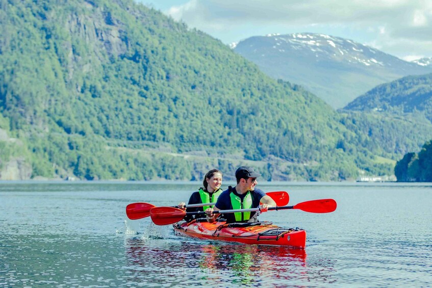Two people kayaking on a calm lake with mountains in the background. 4